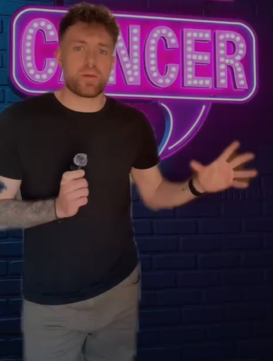 Chris holding a sign for Cancer Research UK